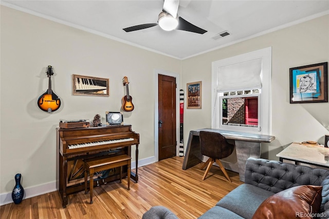 living area with crown molding, light wood-style flooring, ceiling fan, baseboards, and a desk