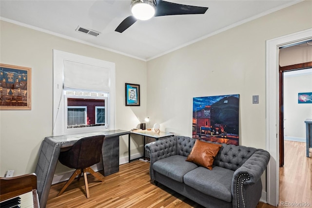 living area featuring wood finished floors, ceiling fan, a desk, and ornamental molding