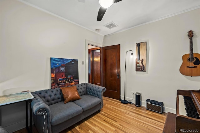 living area with ceiling fan, light wood-type flooring, baseboards, and ornamental molding