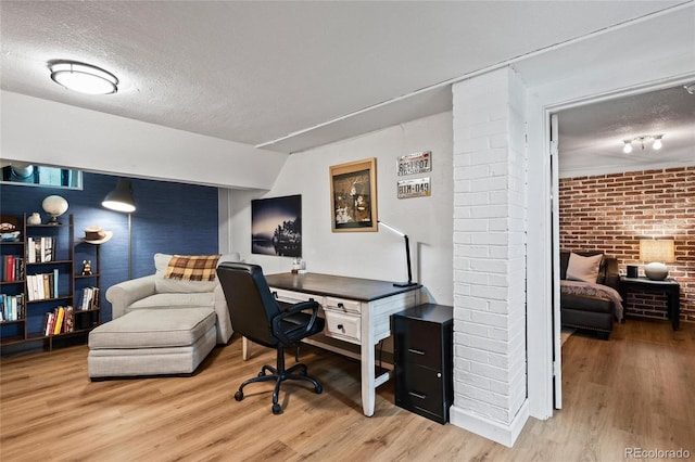 office with brick wall, wood finished floors, and a textured ceiling