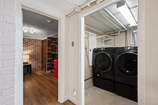 washroom with independent washer and dryer, brick wall, baseboards, and wood finished floors