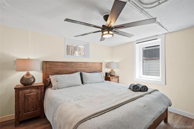 bedroom with wood finished floors, baseboards, a textured ceiling, and a ceiling fan