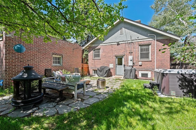 rear view of house with a hot tub, a patio area, brick siding, and central AC unit