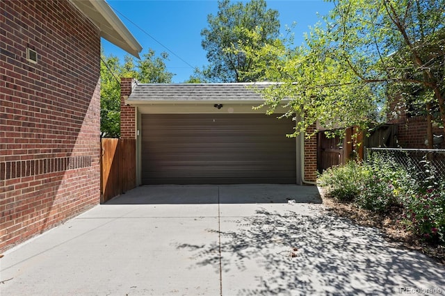 garage with concrete driveway and fence