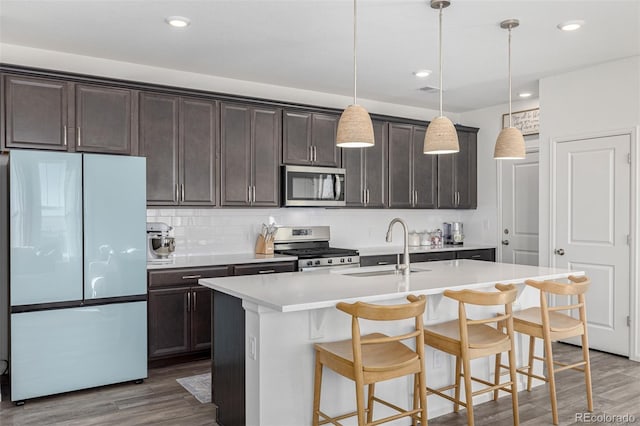 kitchen featuring hardwood / wood-style flooring, appliances with stainless steel finishes, sink, and hanging light fixtures