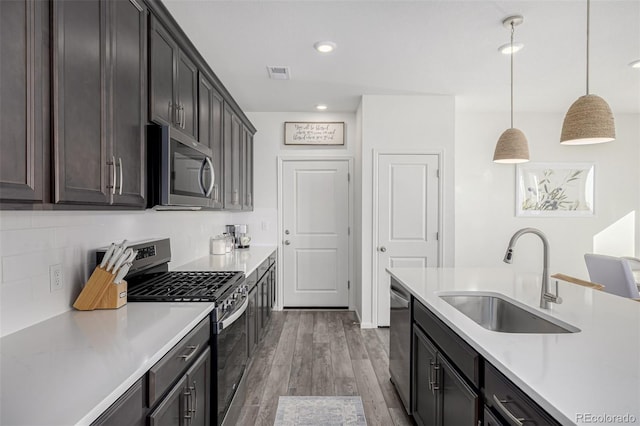 kitchen featuring hanging light fixtures, dark wood-type flooring, sink, dark brown cabinetry, and stainless steel appliances