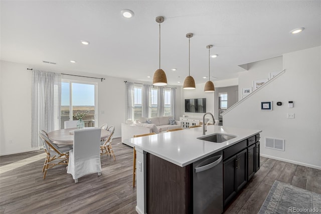 kitchen with dishwasher, an island with sink, sink, decorative light fixtures, and dark hardwood / wood-style flooring