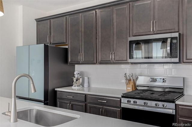 kitchen featuring dark brown cabinetry, tasteful backsplash, appliances with stainless steel finishes, and sink