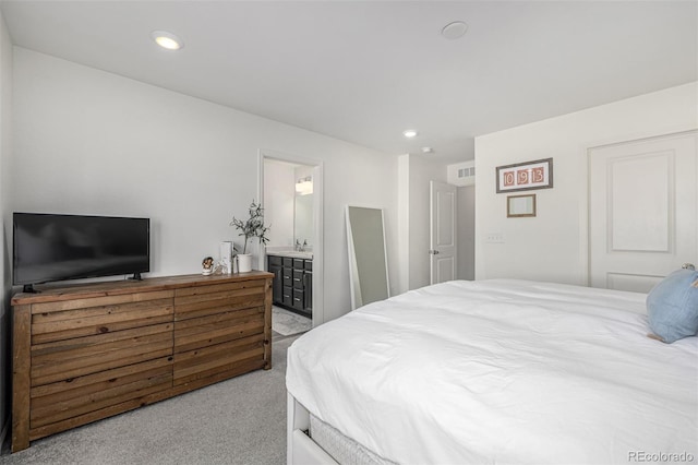 bedroom featuring ensuite bath and light carpet