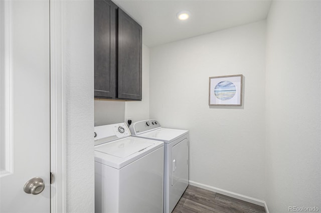 laundry area featuring cabinets, washing machine and dryer, and dark hardwood / wood-style flooring