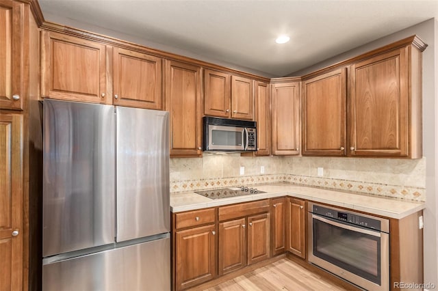 kitchen featuring stainless steel appliances, light wood-type flooring, and decorative backsplash