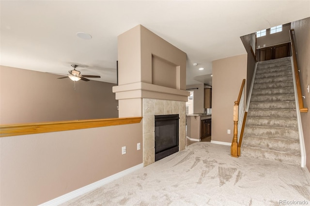 unfurnished living room featuring ceiling fan, a tiled fireplace, and carpet floors