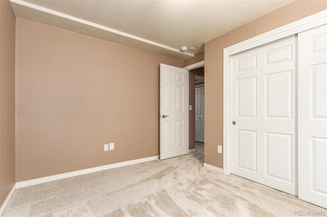 unfurnished bedroom with light colored carpet and a closet