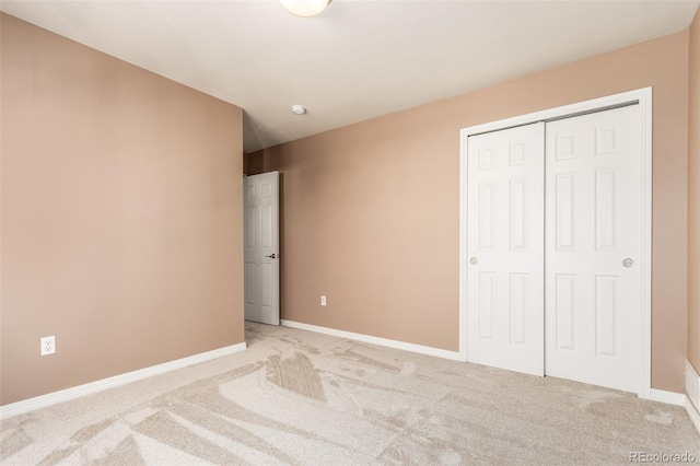 unfurnished bedroom with a closet and light colored carpet