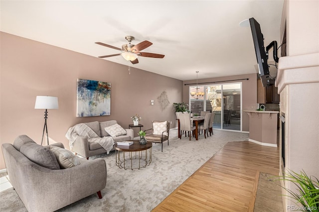 living area featuring ceiling fan with notable chandelier and light wood finished floors