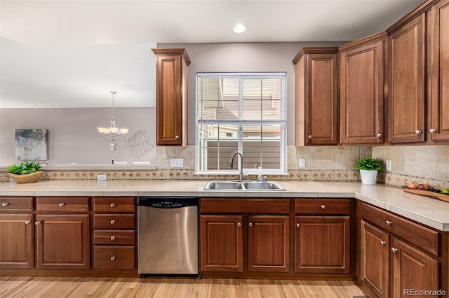 kitchen featuring light countertops, light wood-style flooring, a sink, dishwasher, and a peninsula