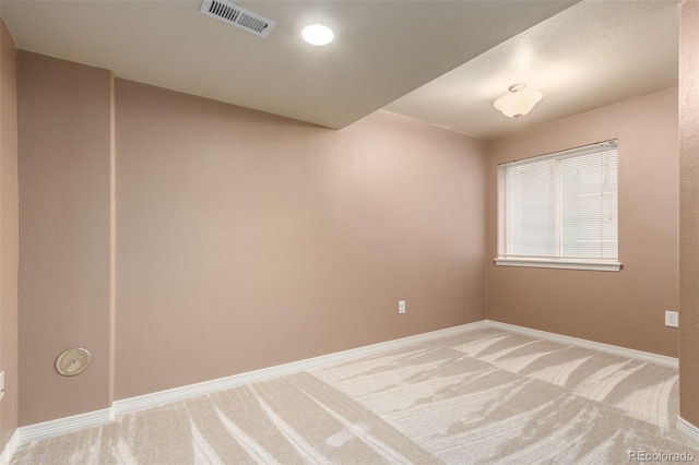 unfurnished room featuring baseboards, visible vents, and light colored carpet