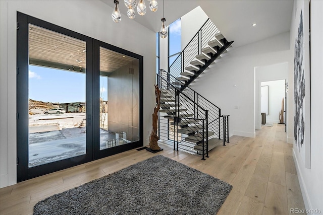 entryway featuring a towering ceiling, baseboards, and wood finished floors