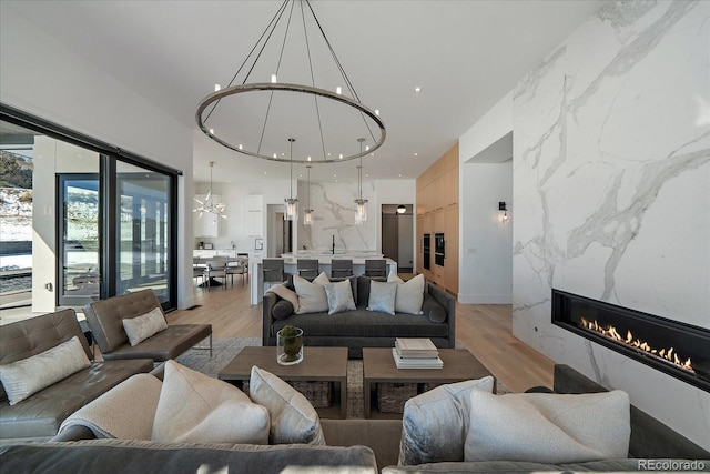 living room featuring light wood finished floors, a fireplace, and an inviting chandelier