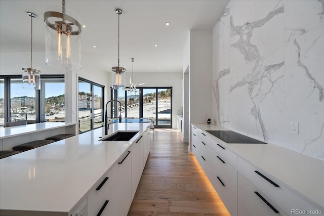 kitchen featuring light wood finished floors, tasteful backsplash, white cabinetry, a sink, and modern cabinets