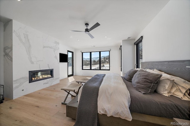 bedroom featuring wood finished floors, visible vents, ceiling fan, and a premium fireplace