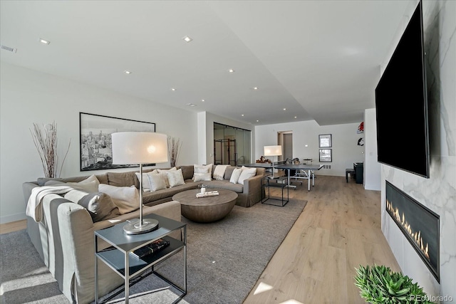 living room with light wood-style flooring, a fireplace, and recessed lighting