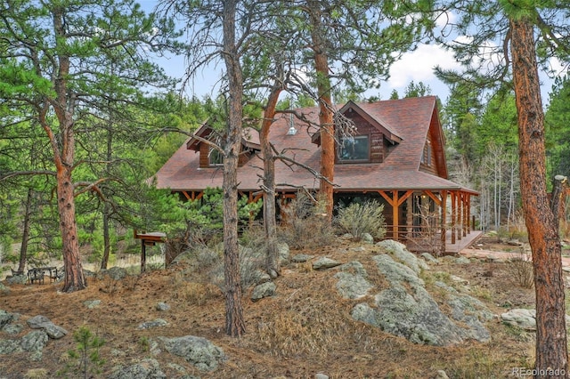 view of side of home featuring a porch and a shingled roof