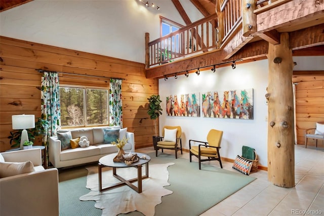 tiled living room with track lighting, baseboards, wooden walls, and high vaulted ceiling