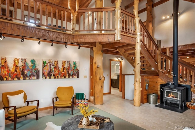 living room with a wood stove, rail lighting, baseboards, a high ceiling, and stairs
