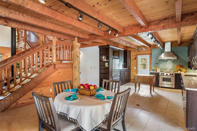dining area featuring wooden walls, light tile patterned flooring, track lighting, beam ceiling, and wooden ceiling