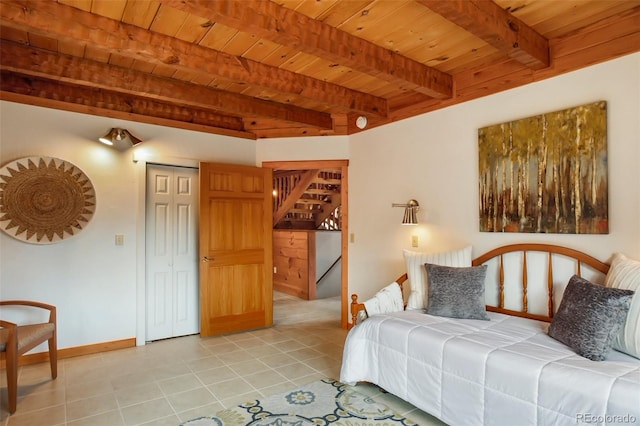 bedroom featuring a closet, beam ceiling, baseboards, wooden ceiling, and light tile patterned floors