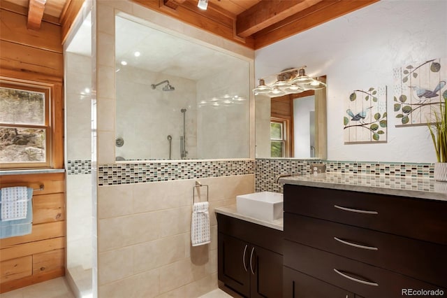 full bath featuring vanity, tasteful backsplash, beamed ceiling, and walk in shower