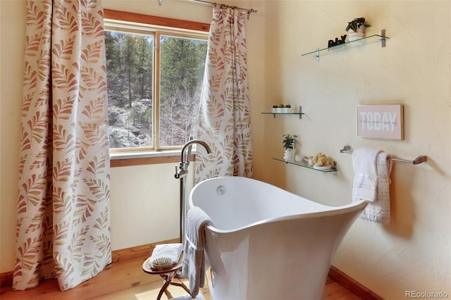 bathroom with a freestanding tub and wood finished floors