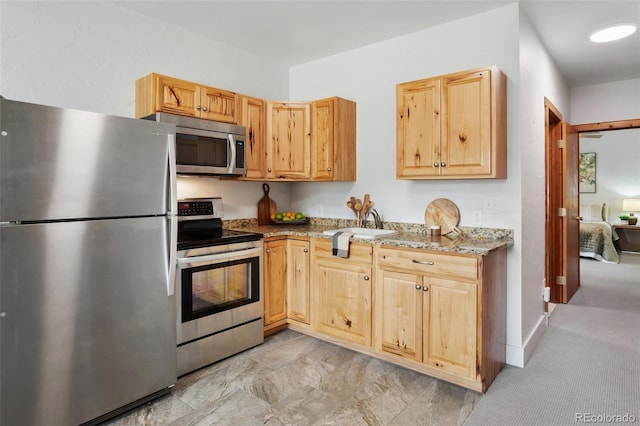 kitchen featuring light brown cabinets, light stone countertops, and stainless steel appliances