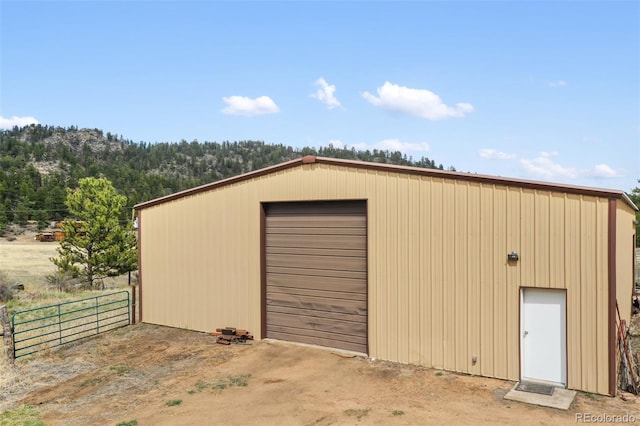 view of outdoor structure with fence and an outbuilding