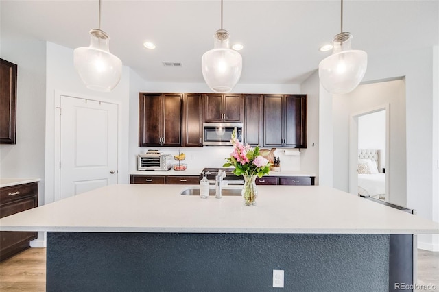 8517 Eckley St, Littleton, CO 80125 - kitchen featuring stainless steel appliances, light countertops, light wood finished floors, dark brown cabinets, and recessed lighting