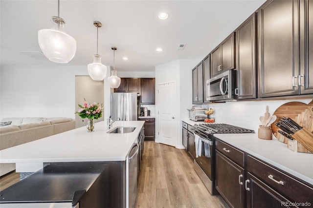 8517 Eckley St, Littleton, CO 80125 - kitchen with appliances with stainless steel finishes, a sink, dark brown cabinets, light wood-style floors, and recessed lighting