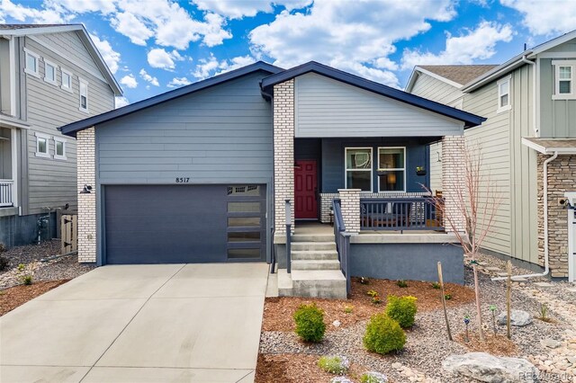 8517 Eckley St, Littleton, CO 80125 - view of front of home featuring covered porch, a garage, driveway, and brick siding