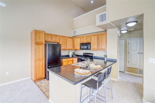 kitchen featuring black appliances, a towering ceiling, dark countertops, a sink, and light colored carpet