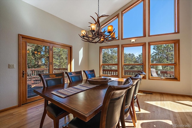 dining room with high vaulted ceiling, a notable chandelier, visible vents, baseboards, and light wood-style floors