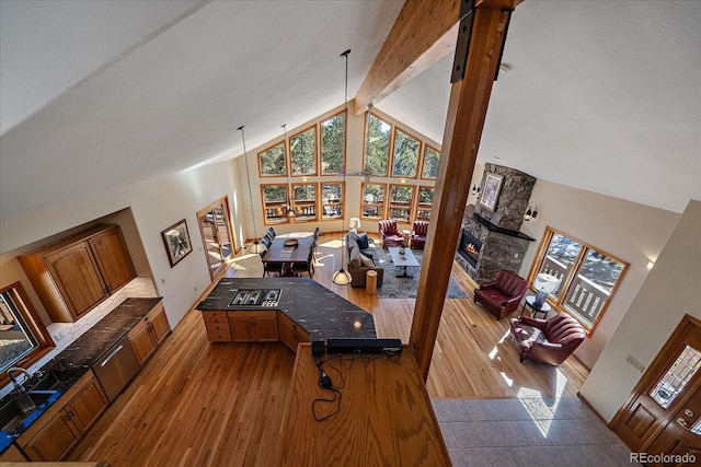 interior space featuring high vaulted ceiling, beam ceiling, a fireplace, and wood finished floors