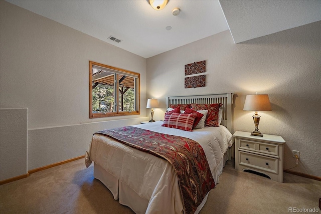 carpeted bedroom featuring baseboards, visible vents, and a textured wall