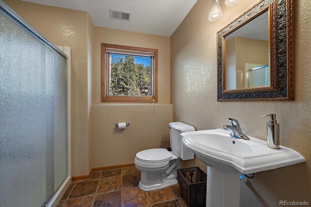 bathroom featuring toilet, visible vents, baseboards, a stall shower, and stone tile flooring