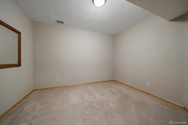 empty room with carpet floors, visible vents, and baseboards