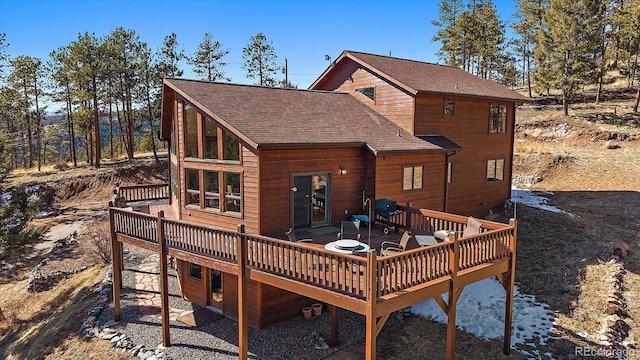 rear view of property featuring a deck and roof with shingles