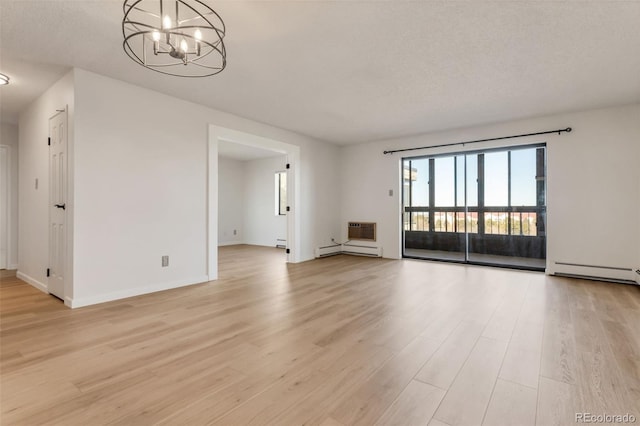 empty room with a textured ceiling, light hardwood / wood-style flooring, a baseboard heating unit, and a notable chandelier