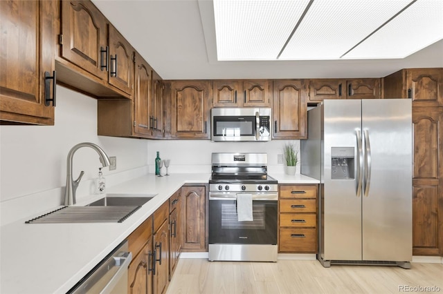 kitchen with sink, light wood-type flooring, and appliances with stainless steel finishes