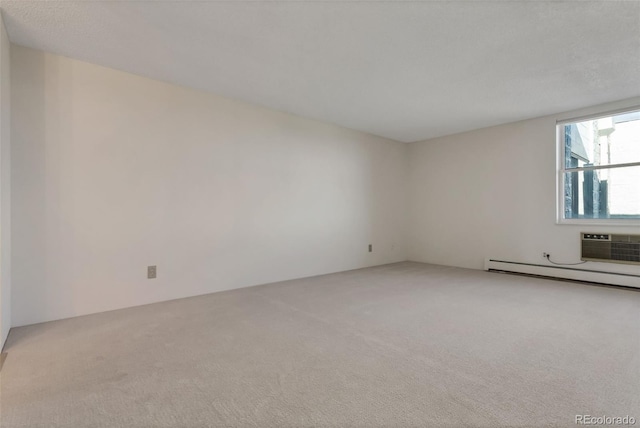 empty room with a wall unit AC, a baseboard heating unit, and light carpet