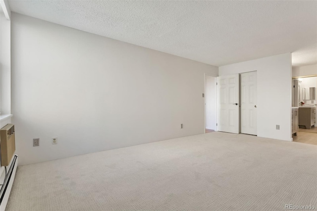 unfurnished bedroom with a textured ceiling, ensuite bath, a baseboard radiator, a closet, and light colored carpet