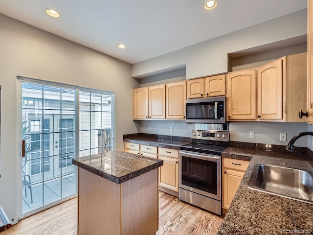 5155 W Quincy Ave Unit J103, Denver, CO 80236 - kitchen featuring appliances with stainless steel finishes, light brown cabinetry, tile counters, a center island, and light wood-style flooring